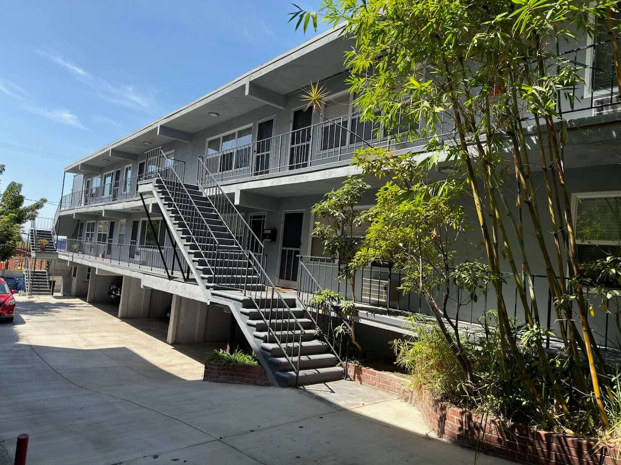 Front view of a multi-unit building with stairs and landscaping. (photo 2 of 9)