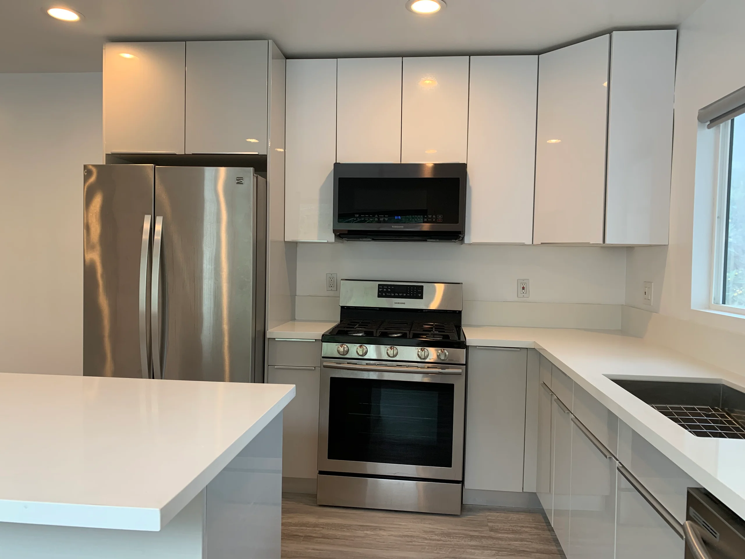 Modern kitchen with stainless steel appliances and white countertops. (photo 2 of 25)