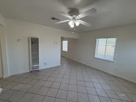 Spacious living room with tile flooring and a ceiling fan. (photo 2 of 5)
