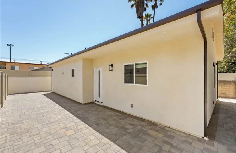Exterior view of a house with a paved area and palm trees. (photo 1 of 9)