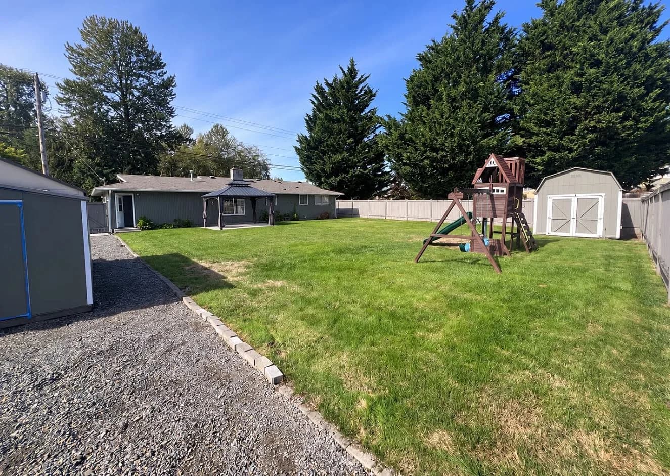 Spacious backyard featuring a grass lawn, a playset, and a storage shed. (photo 2 of 19)