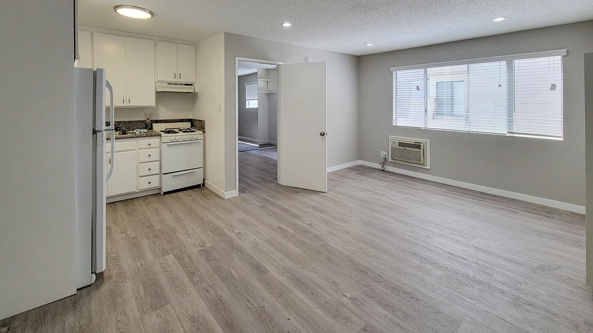 Spacious living area with hardwood flooring and an adjacent kitchen featuring stainless appliances. (photo 2 of 16)