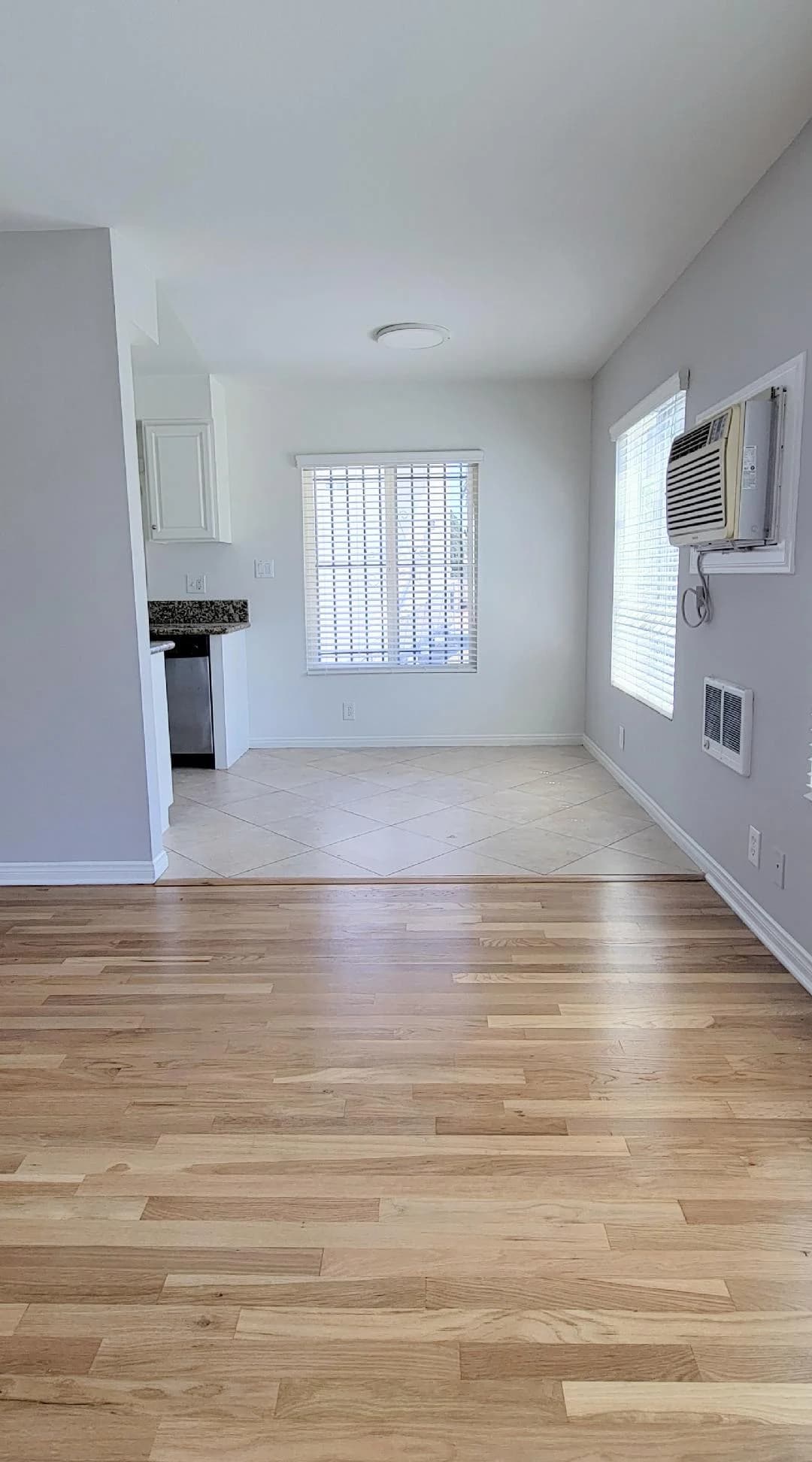 Spacious living room with hardwood flooring and adjacent kitchen area. (photo 1 of 8)