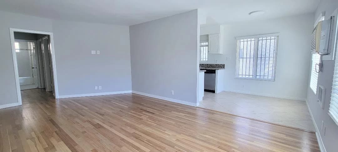 Spacious living room with hardwood flooring and access to a kitchen with granite countertops. (photo 2 of 8)